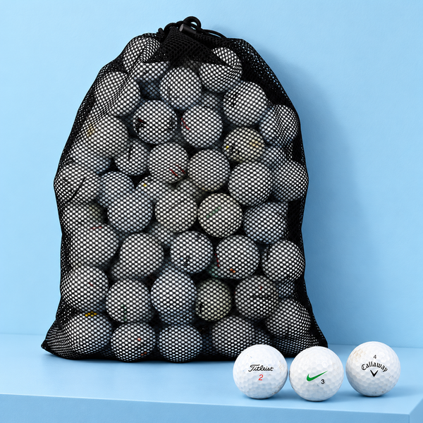 Black mesh bag full of used golf balls on a blue shelf, with Titleist, Nike and Callaway balls in front