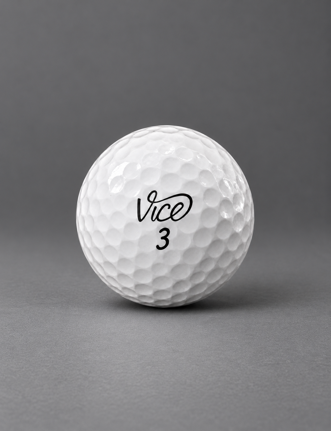 Mint condition Vice golf ball with no visible marks on a graphite surface